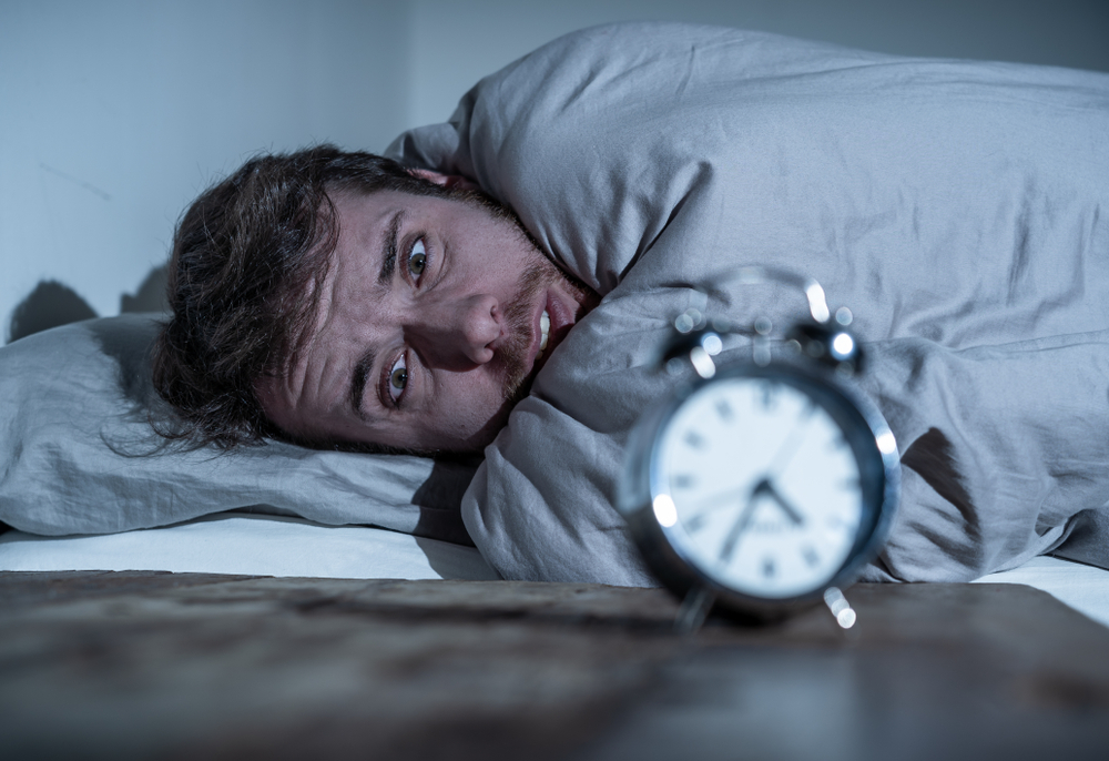 uomo che non dorme e guarda una sveglia