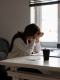 Donna seduta alla scrivania con la testa tra le mani, visibilmente stanca e sotto stress, simbolo del rientro lavorativo faticoso