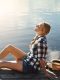 ragazza rilassata al sole in riva al lago, simbolo di benessere mentale e equilibrio emotivo naturale