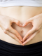 Persona che forma un cuore con le mani sull’addome, simbolo di intestino sano e connessione con il sistema immunitario